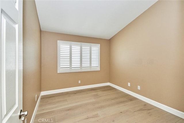 spare room with vaulted ceiling and light hardwood / wood-style floors