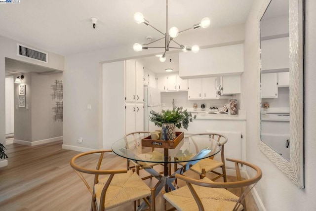 dining space with light hardwood / wood-style flooring and a notable chandelier