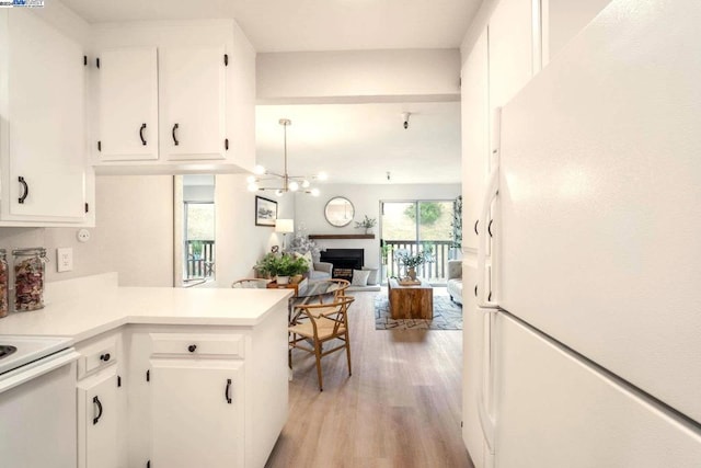 kitchen with white cabinetry, a notable chandelier, kitchen peninsula, light hardwood / wood-style floors, and white appliances