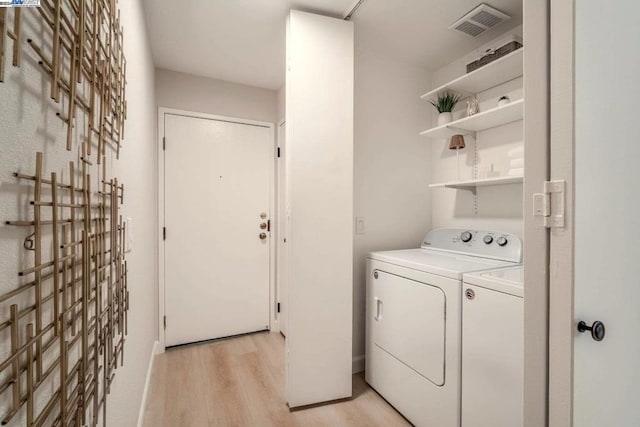 laundry room featuring washing machine and dryer and light hardwood / wood-style floors