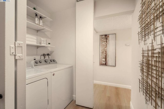 washroom with a textured ceiling, washing machine and dryer, and light hardwood / wood-style flooring