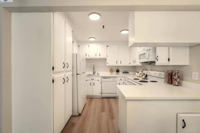 kitchen with white cabinets, white appliances, sink, and light hardwood / wood-style flooring