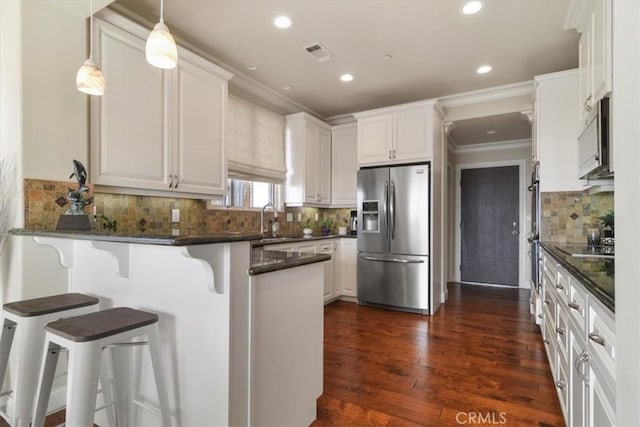 kitchen featuring white cabinetry, a breakfast bar area, kitchen peninsula, and appliances with stainless steel finishes