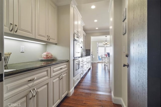 hall with an inviting chandelier, ornamental molding, and dark hardwood / wood-style floors