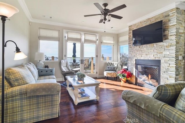 living room with ornamental molding, a stone fireplace, plenty of natural light, and dark hardwood / wood-style floors