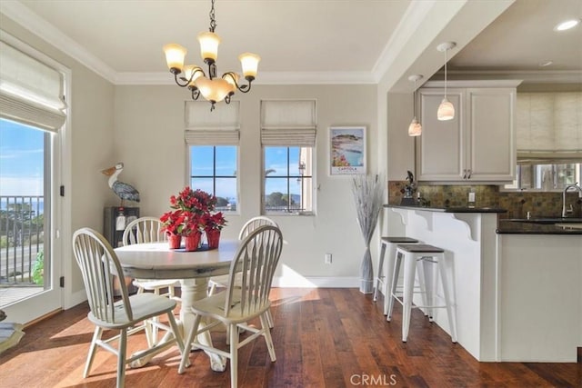 dining area with crown molding, dark hardwood / wood-style floors, sink, and a notable chandelier