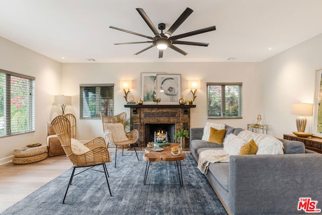 living room with ceiling fan, light wood-type flooring, and a fireplace