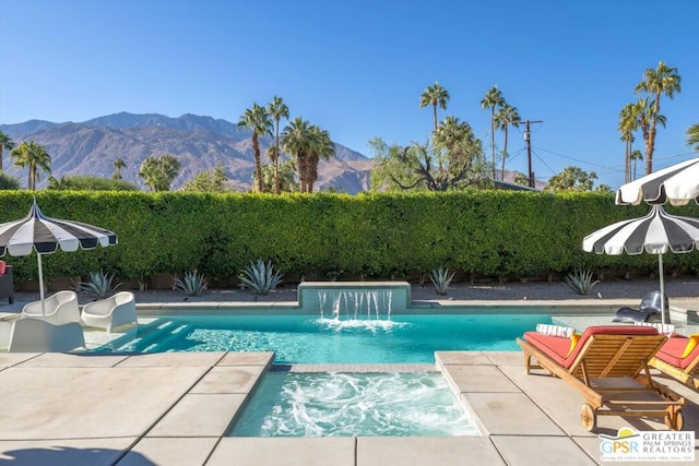 view of swimming pool featuring pool water feature, a mountain view, and a patio area