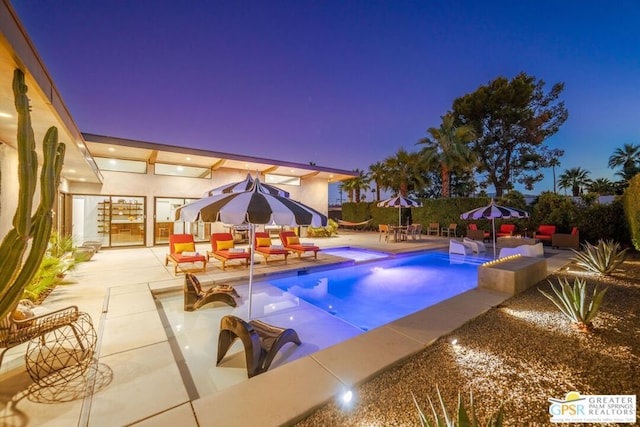 pool at dusk with a patio and a hot tub