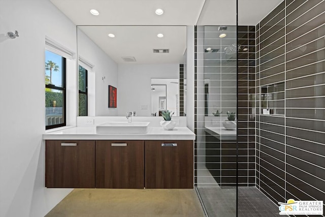 bathroom with a tile shower and vanity