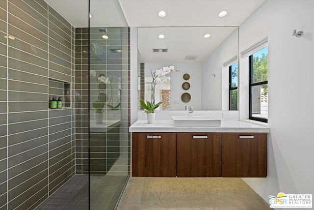 bathroom with a tile shower and vanity