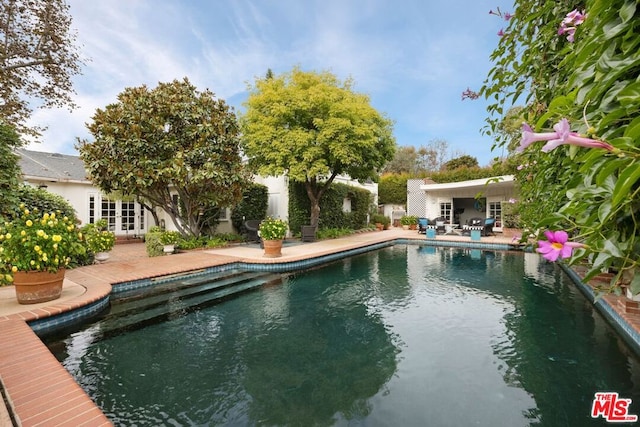 view of swimming pool featuring french doors and a patio