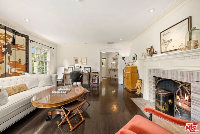 living room featuring dark hardwood / wood-style floors, ornamental molding, and a brick fireplace