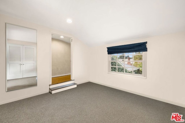 spare room featuring carpet and lofted ceiling