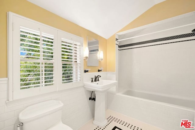 bathroom with tile walls, tiled shower / bath combo, vaulted ceiling, and toilet