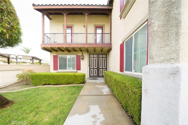 entrance to property featuring a yard and a balcony