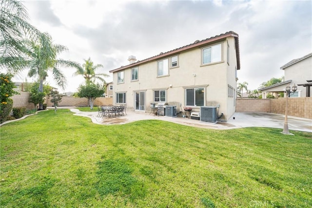 rear view of property featuring a yard, a patio, and central air condition unit