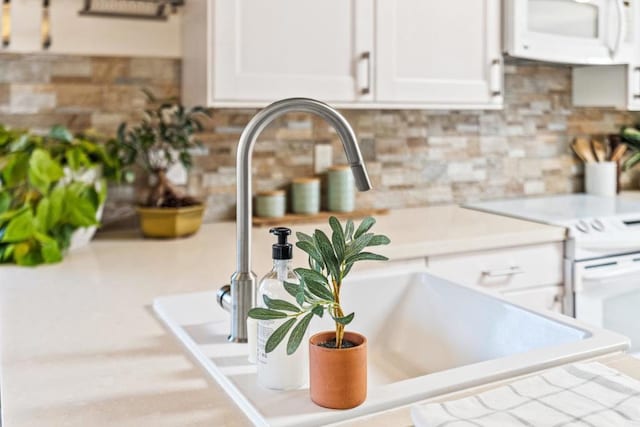 interior details featuring white appliances, decorative backsplash, and white cabinets