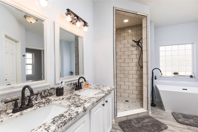 bathroom featuring a freestanding tub, tiled shower, a sink, and double vanity