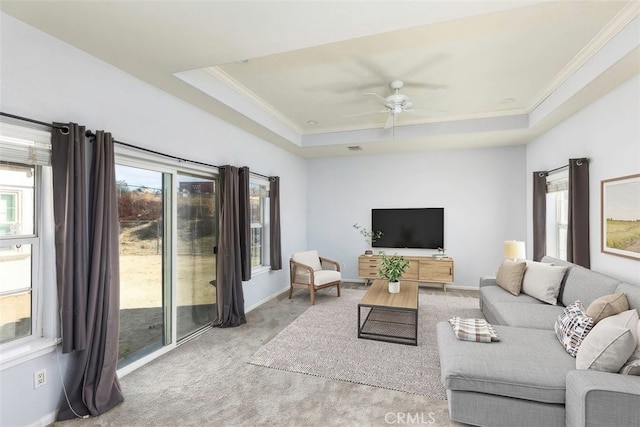 living room featuring crown molding, a tray ceiling, light colored carpet, and plenty of natural light