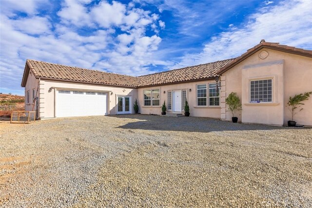 38752 Ruth Rd, Hemet, CA 92544 - mediterranean / spanish-style home with french doors, an attached garage, stucco siding, a tiled roof, and gravel driveway