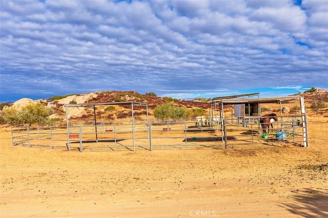 view of play area featuring an outbuilding, a rural view, an exterior structure, and a mountain view