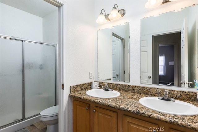 full bath with a stall shower, a sink, toilet, and double vanity