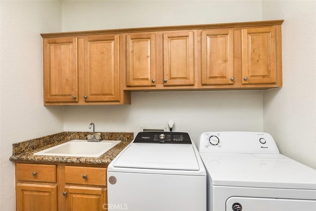 washroom with washing machine and dryer, cabinet space, and a sink