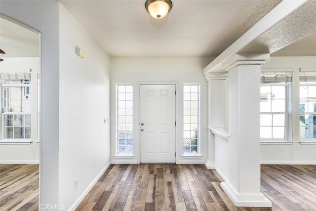 entryway with decorative columns, a textured ceiling, baseboards, and wood finished floors