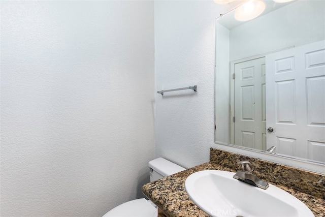 bathroom with a textured wall, a sink, and toilet