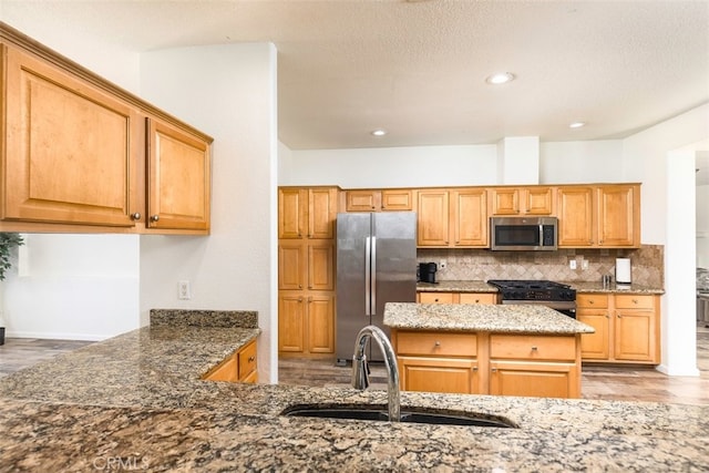 kitchen featuring stainless steel appliances, a sink, dark stone countertops, and tasteful backsplash