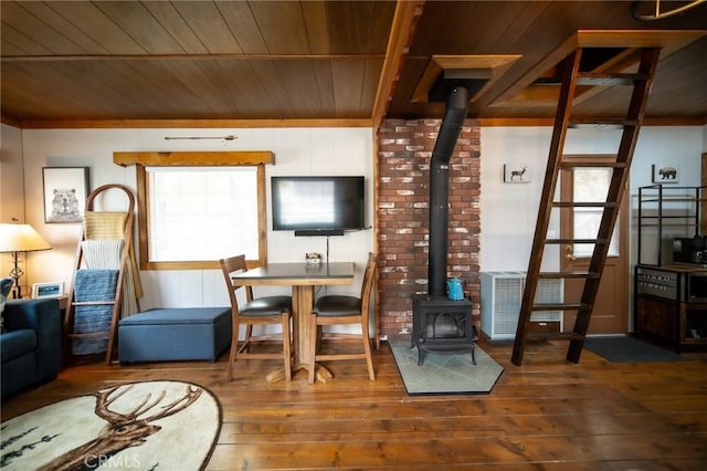 interior space with hardwood / wood-style flooring, a wood stove, ornamental molding, and wood ceiling