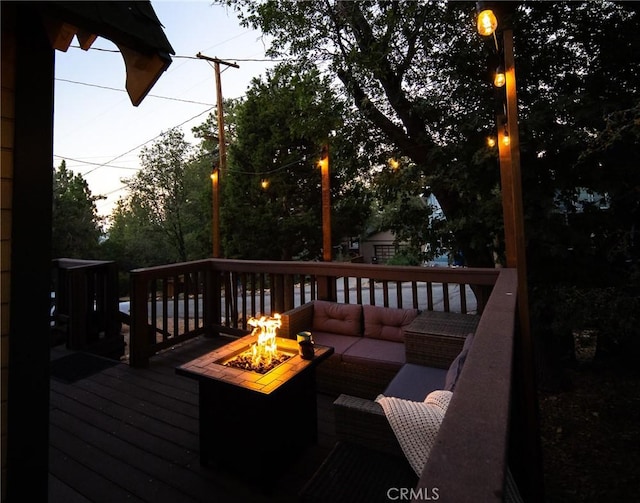 deck at dusk with an outdoor living space with a fire pit