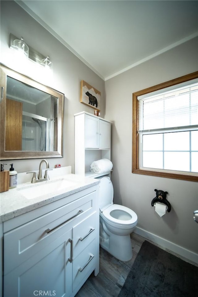 bathroom featuring an enclosed shower, vanity, crown molding, wood-type flooring, and toilet