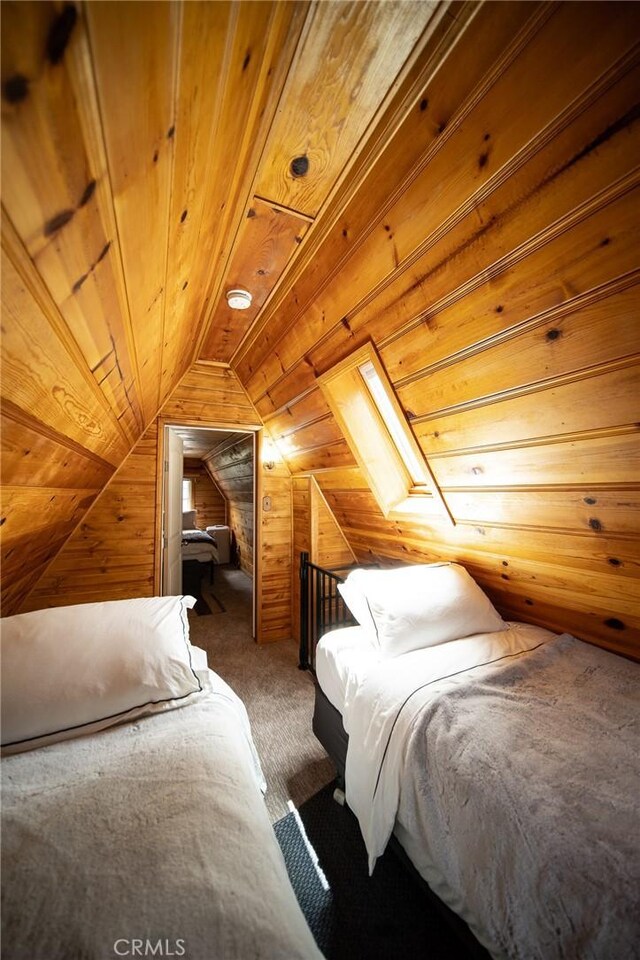 unfurnished bedroom with vaulted ceiling with skylight, dark carpet, wood ceiling, and wood walls