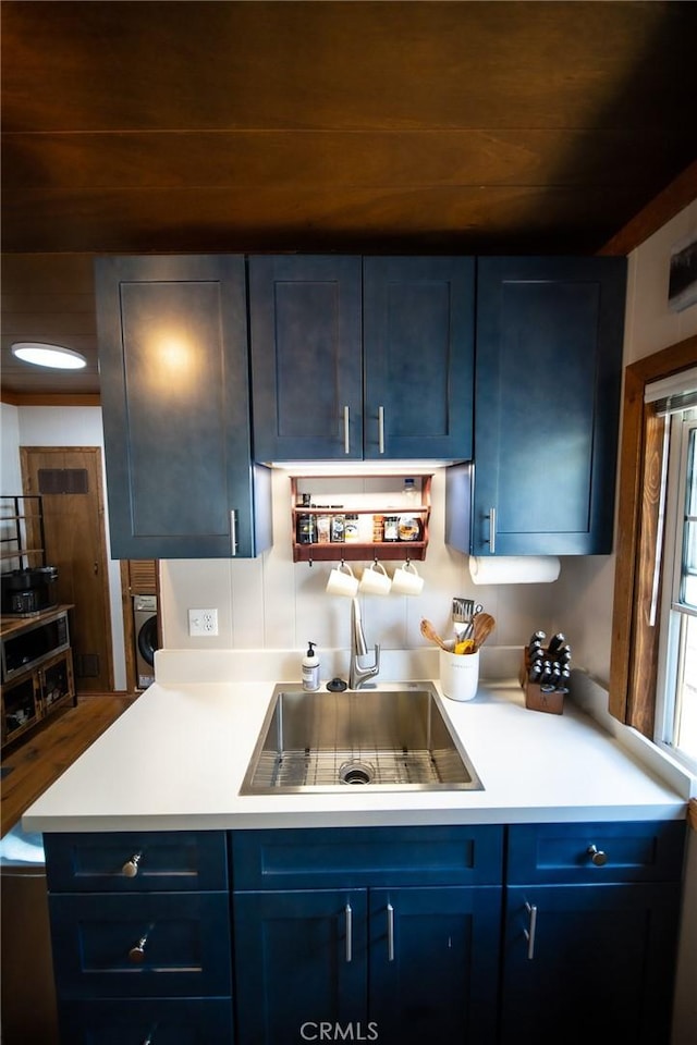 kitchen with washer / dryer, blue cabinets, and sink