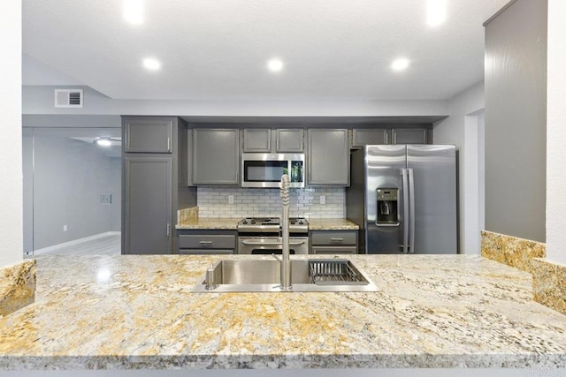 kitchen featuring visible vents, decorative backsplash, appliances with stainless steel finishes, light stone counters, and gray cabinetry