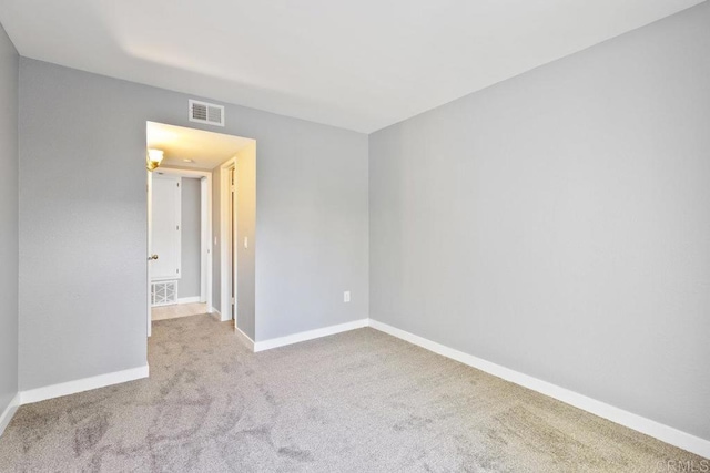 spare room with carpet, visible vents, and baseboards