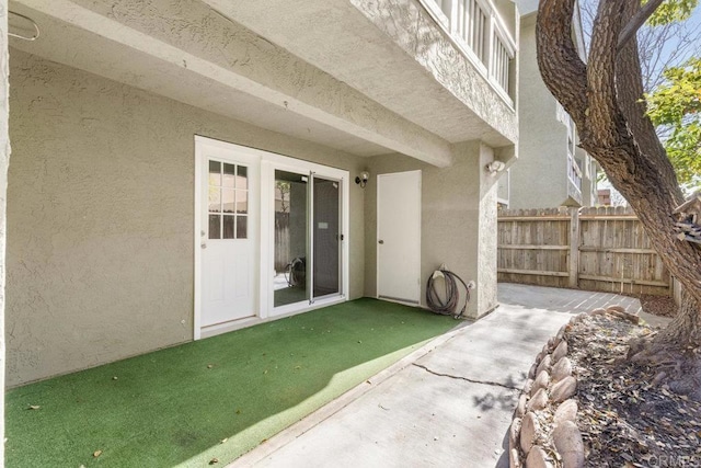 doorway to property featuring fence and stucco siding