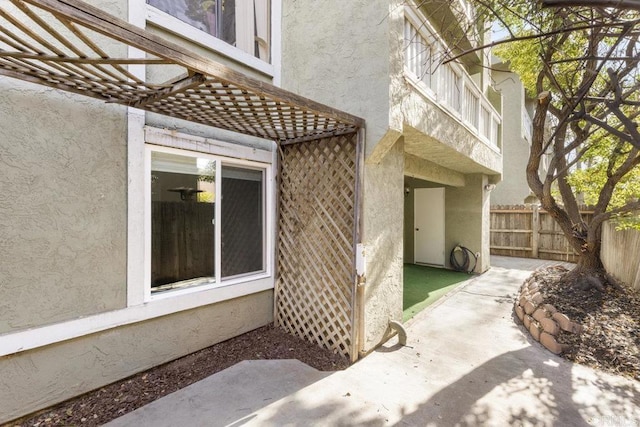 doorway to property with fence and stucco siding