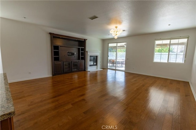 unfurnished living room with hardwood / wood-style flooring and a notable chandelier