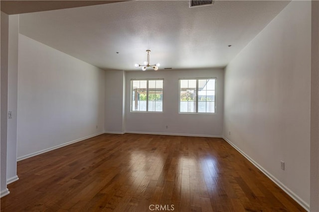 spare room featuring dark hardwood / wood-style flooring and a chandelier