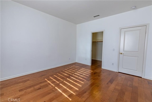 unfurnished bedroom featuring a closet, a spacious closet, and hardwood / wood-style flooring