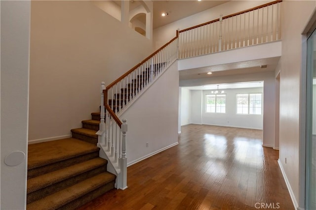 stairway featuring a towering ceiling and hardwood / wood-style floors