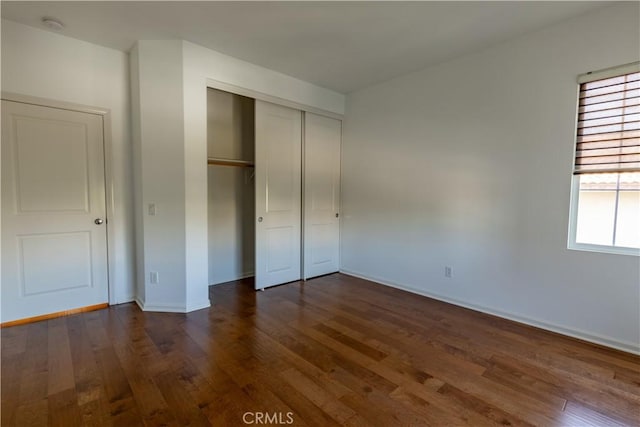 unfurnished bedroom featuring dark hardwood / wood-style floors and a closet