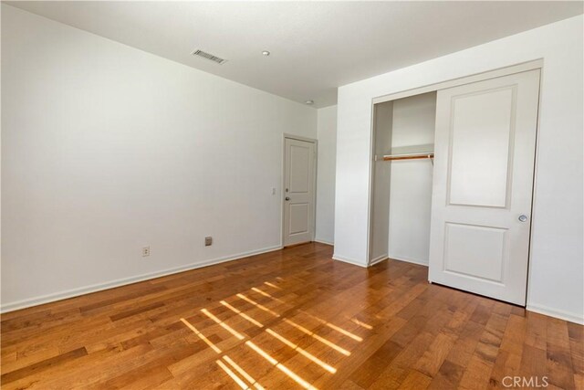 unfurnished bedroom with hardwood / wood-style floors and a closet