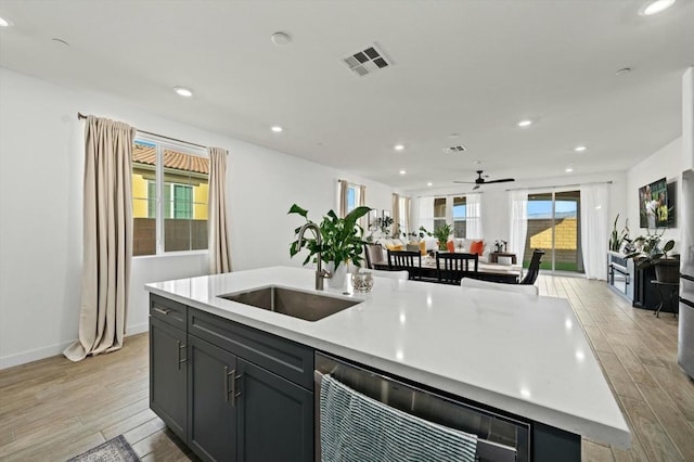 kitchen with light hardwood / wood-style floors, a center island with sink, a healthy amount of sunlight, and sink