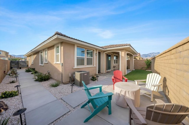 rear view of property with a mountain view, central air condition unit, and a patio