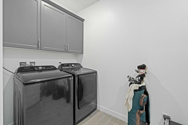 laundry area featuring light hardwood / wood-style floors, cabinets, and washing machine and clothes dryer