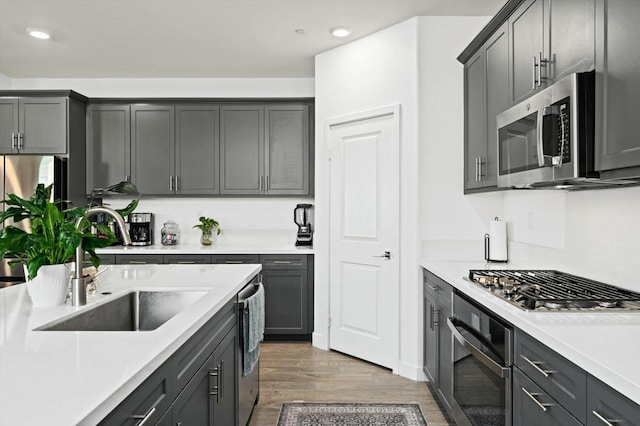 kitchen featuring gray cabinetry, sink, wood-type flooring, and stainless steel appliances